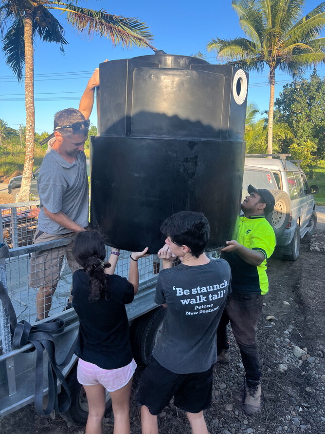 Team work makes the dream work - unloading a new septic tank for installation.