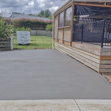 smaller smooth grey concrete driveway next to house with wooden patio