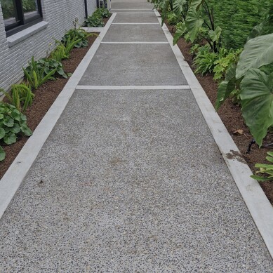 Garden path with light grey concrete border around pebbled darker grey concrete, going down side of house