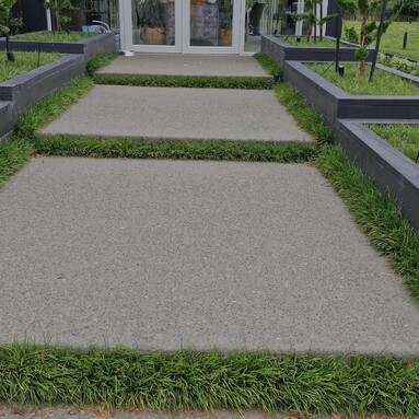 large square exposed aggregate concrete pavers surrounded by grass leading to house