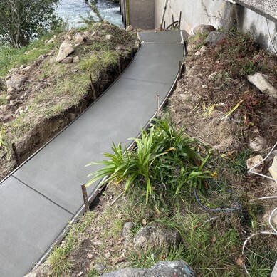 dark grey concrete footpath leading down river bank