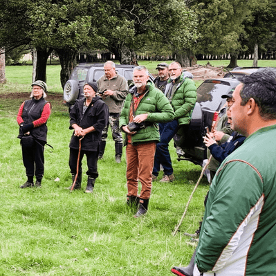 Upper Waipoua Kaitiaki catchment group members standing in a paddock listening to a history talk