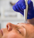 A nanopusion pro pen being using on a lady in the salon by a beauty therapist wearing purple disposable gloves