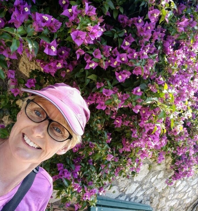 A woman standing by a wall of flowers