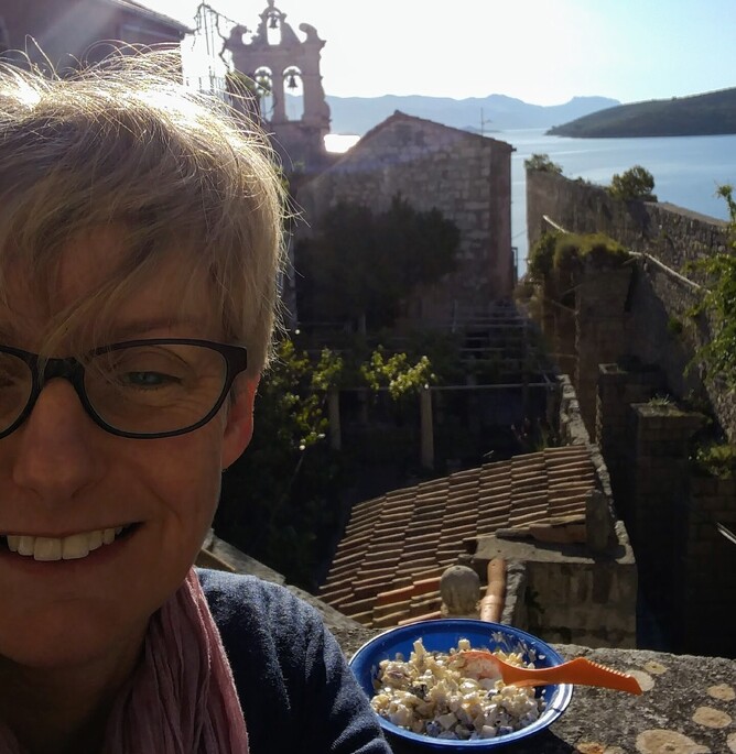 Woman eating breakfast on balcony in Korcula, Croatia.