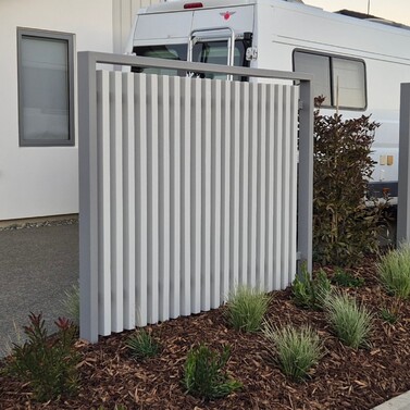 Modern white vertical slat privacy screen beside driveway with planting
