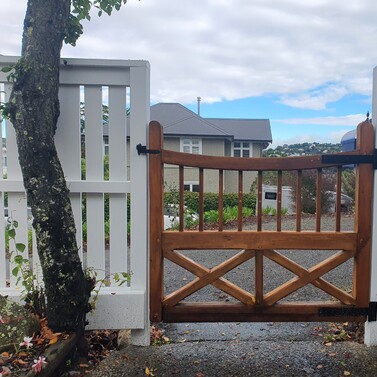 Custom timber gate with white fence in Nelson garden