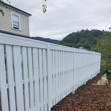 Long white timber fence along boundary with fresh landscaping