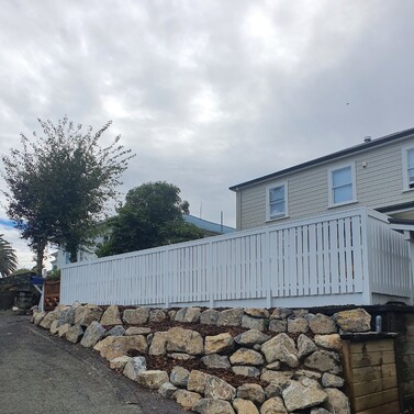 White timber fence above rock retaining wall in residential backyard