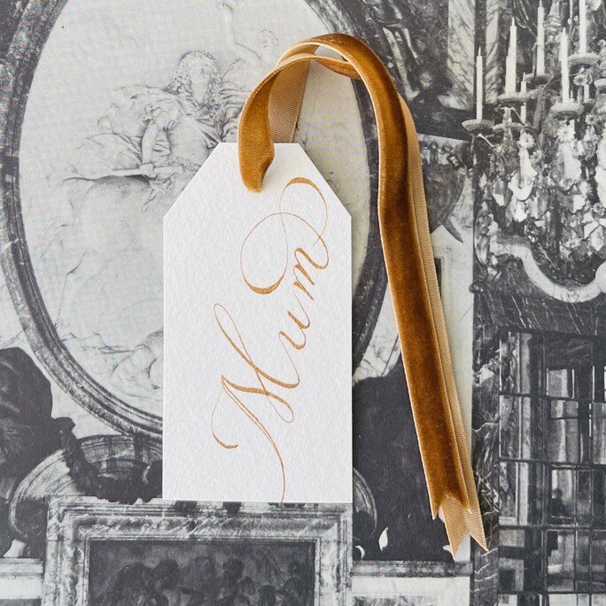 A collection of merry christmas gift tags written in walnut ink and sitting in one of our gift tag jars