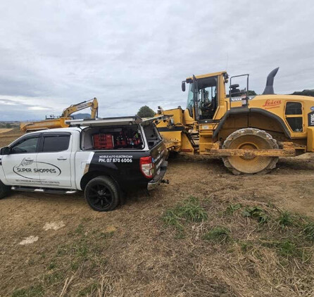 A ute and digger parked in a paddock