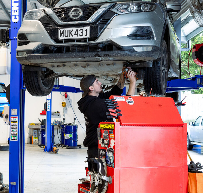 Man servicing a car, standing underneath it