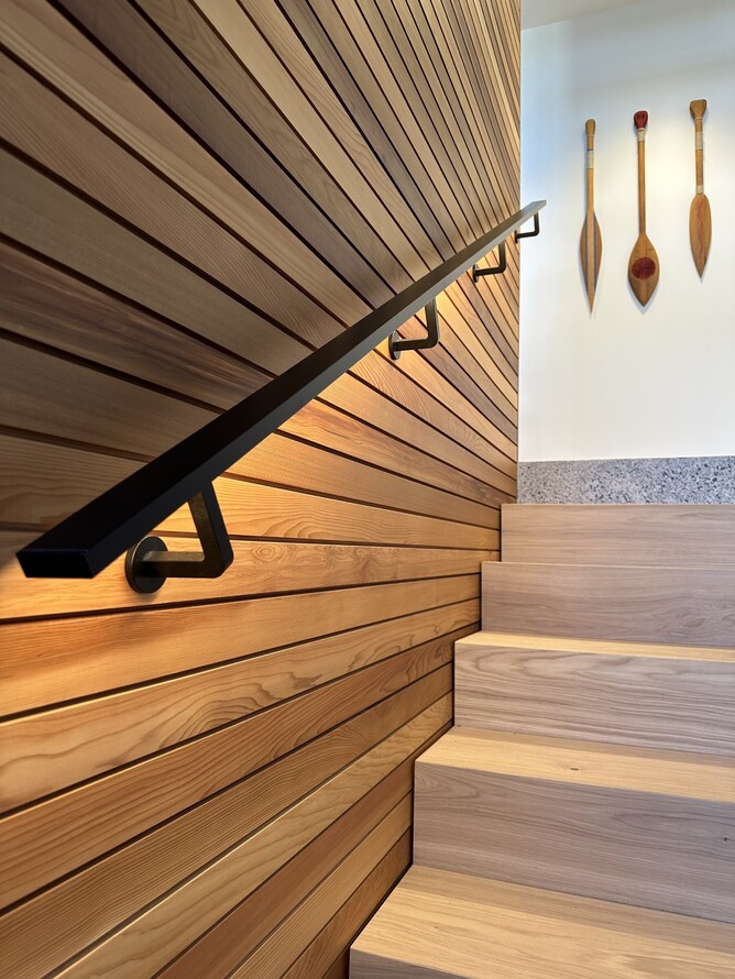 High-end stairway with black metal handrail, wooden slat walls, and integrated lighting