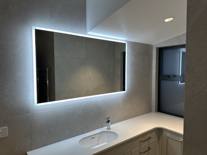 Large rectangular bathroom mirror with custom LED lighting in new build Maungatapu home