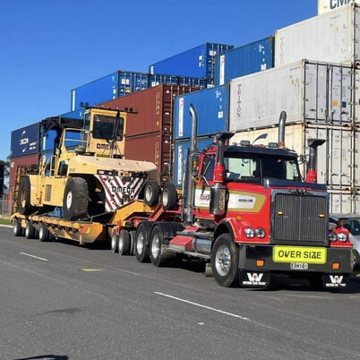 Rowes truck hauling heavy machinery