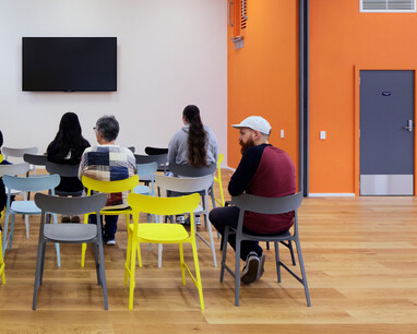picture from behind of people using one of our activity rooms. There is a wall mounted TV in the background.