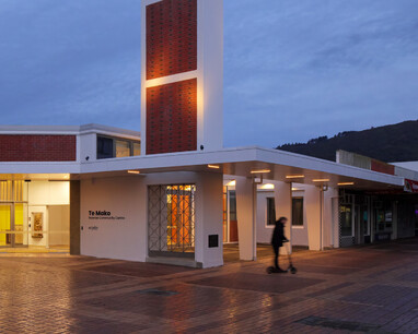 A photo of Te Mako from outside in the evening, the lights are shining through the front doors.