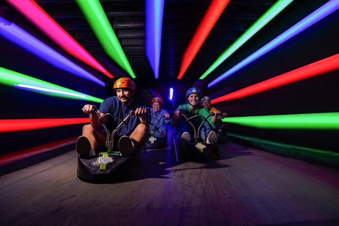 Night luge ride in Rotorua zooming through a tunnel lit with colourful neon lights