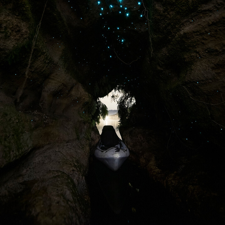Kayak sitting inside a glow worm cave looking towards the lake as dusk falls