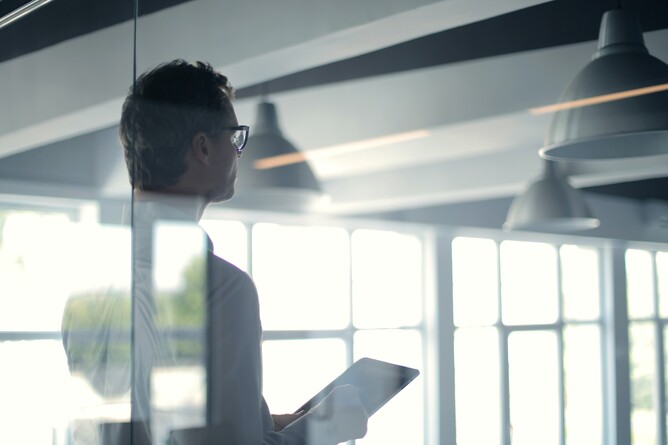 Person holding a tablet, looking out a window, representing GGA's approach to risk governance