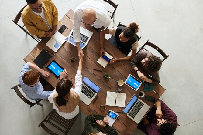 Top view of a group of people collaborating around a table, relevant to GGA's insights on governance and decision-making