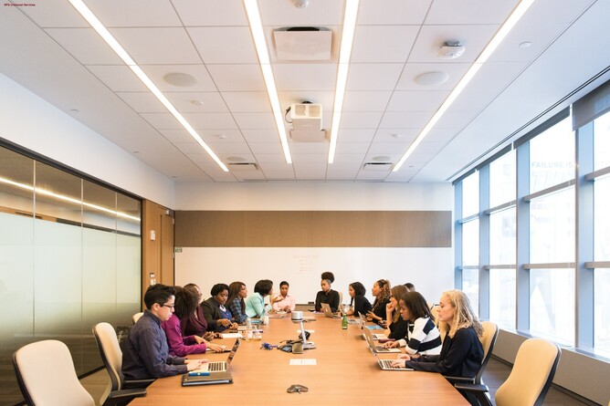 A group of people sitting at a long conference table in a modern boardroom