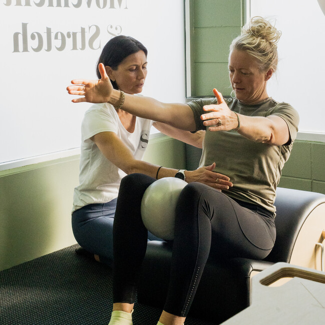 Image of instructor showing a woman how to build core muscles using Pilates exercises at Self, wellness studio in Alexandra.
