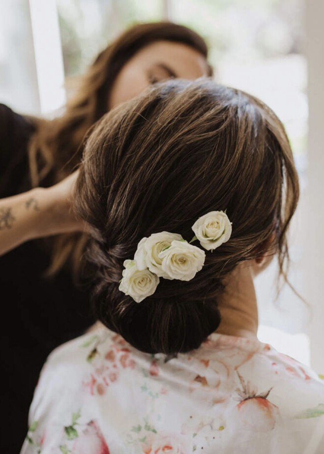 Georgie styling a beautiful low bun updo with white flowers tucked in.