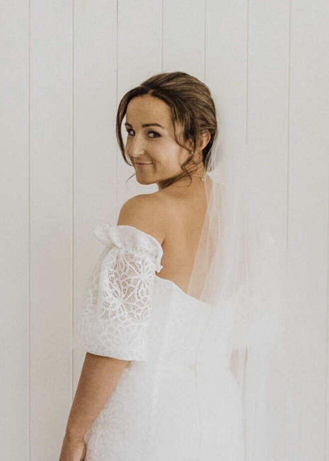 A bride looking back over her shoulder towards the camera, hair and makeup by Georgie.