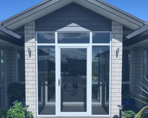 Image of a residential home with a glass door & glass encased entry eway.