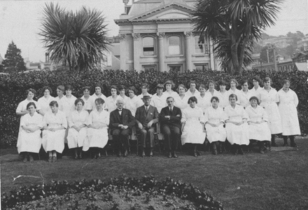 First draft of dental nurse students with Richmond Dunn (Director of the dental nurse training school), Colonel Thomas Hunter (Director of the Division of Dental Hygiene), and James Parr (Minister of Public Health), 1922. Early Period [of Dental School] [Archives Reference: ABKI 667 W4078 1/] Archives New Zealand, The Department of Internal Affairs Te Tari Taiwhenua.