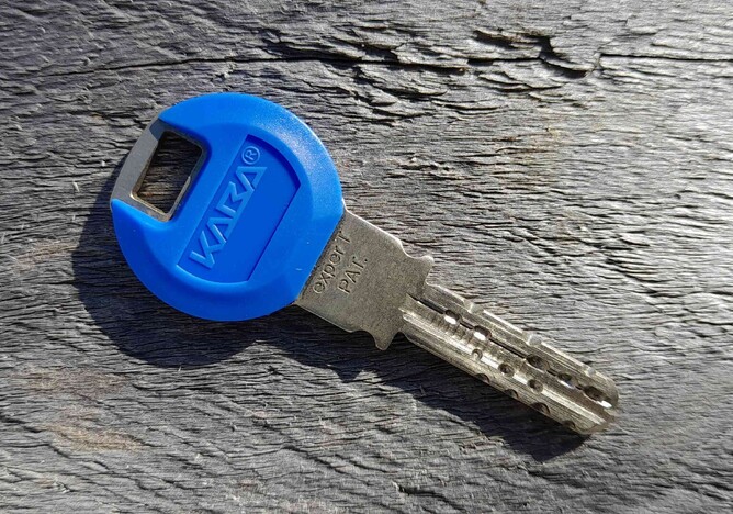 A photo of a blue Kaba high security key on a wood surface