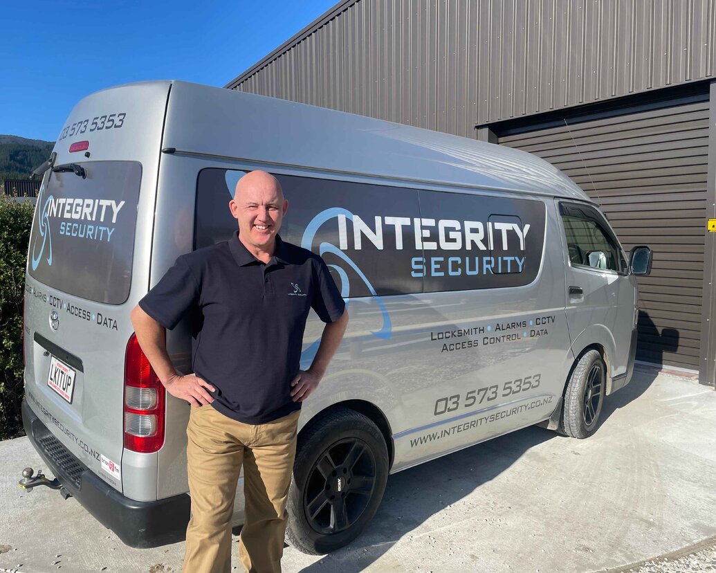 Integrity Security mobile workshop displaying logo and telephone number signage. With a man stood outside the van. The owner.