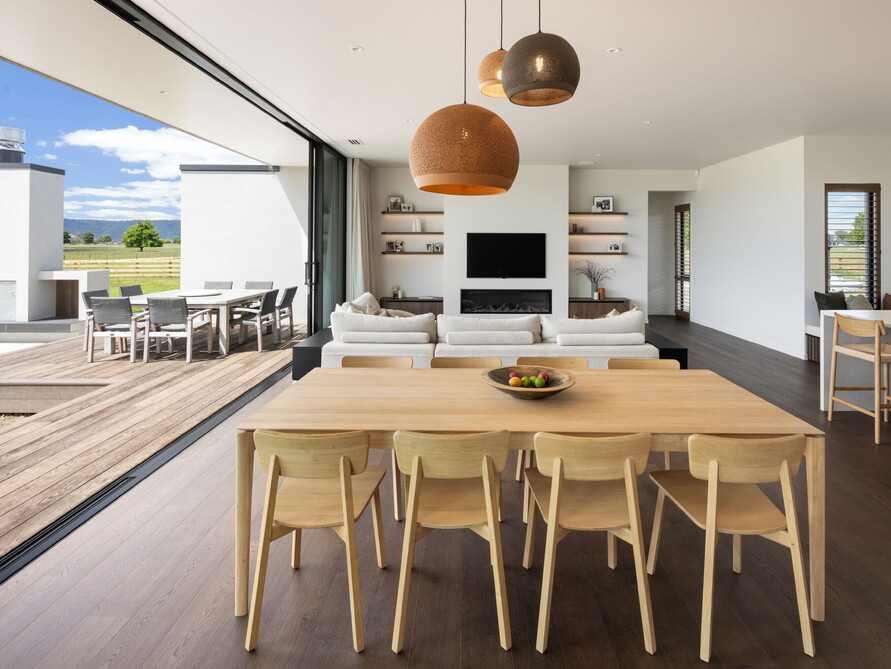 This spacious open-plan living space has been designed and built using earthy wood tones that flow through to the outdoors.