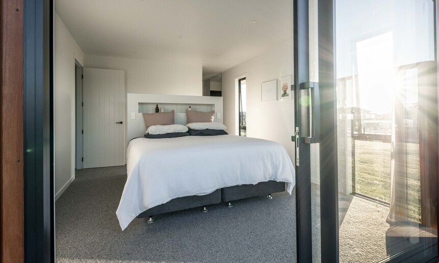 This small bedroom features carefully positioned windows that bring the outside in, showcasing this custom-built home.