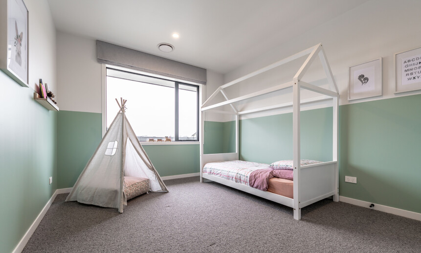 Playfully designed kids’ room with half-height painted walls and cheerful styling in this new house build.