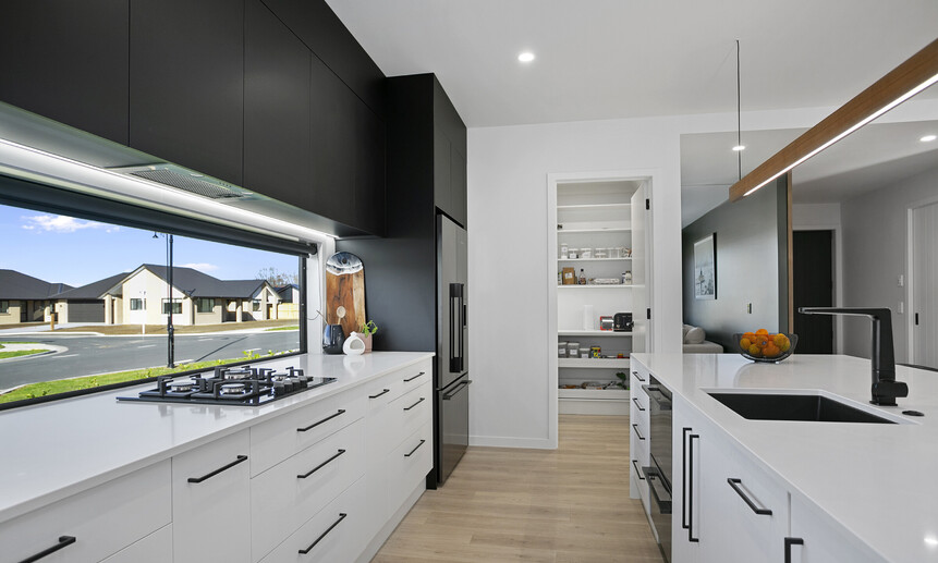 White benchtops and cabinetry with custom black upper cabinetry create a stark contrast, showcasing the custom designed home  
