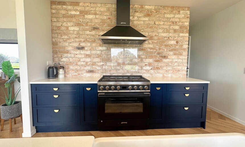 This unique kitchen has a brick wall and custom blue cabinetry makes for a one-of-a-kind design and build.