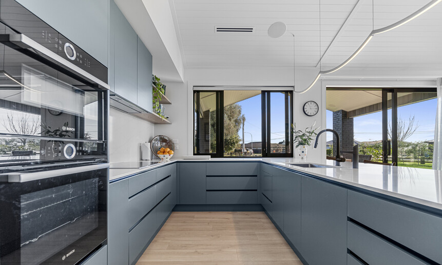The sleek modern kitchen has marble benchtops & a slider kitchen window for entertaining guests in this Cambridge new build. 