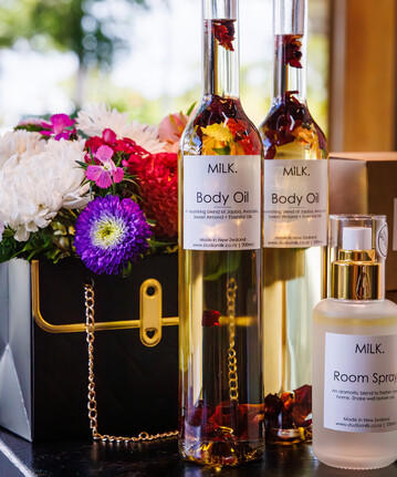 A small flower arrangement with body oil in tall glass bottles.