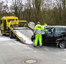 Tow truck operator putting crashed car onto truck