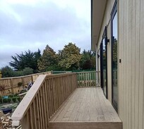 Timber deck with handrails and stair access built alongside a residential home – crafted by professional deck builders in Canterbury.