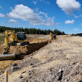 Two Komatsu excavators performing site cuts on a hilltop with panoramic views – trusted earthmoving contractors Canterbury.