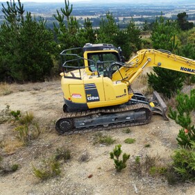 Komatsu excavator clearing rugged hillside terrain in Canterbury – reliable earthworks and excavation services North Canterbury.