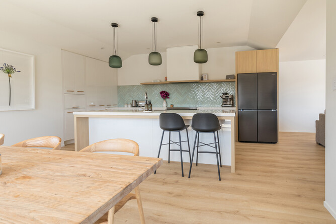 AFTER: Original kitchen cabinets with updated oak accents, new rangehood and modern pendant lighting. The oak-look laminate floor adds warmth to the room.