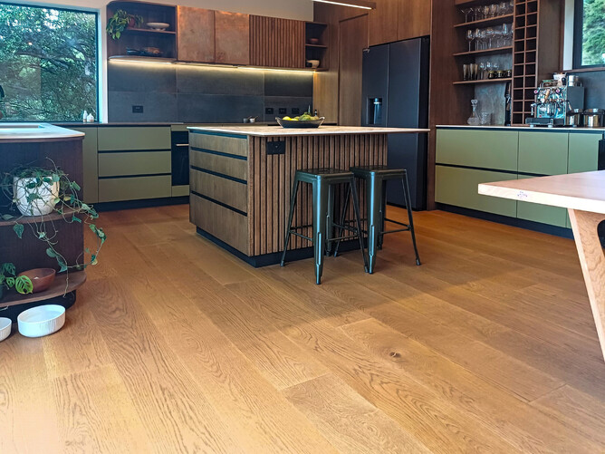 A modern kitchen with green and black accents and natural vintage oak flooring