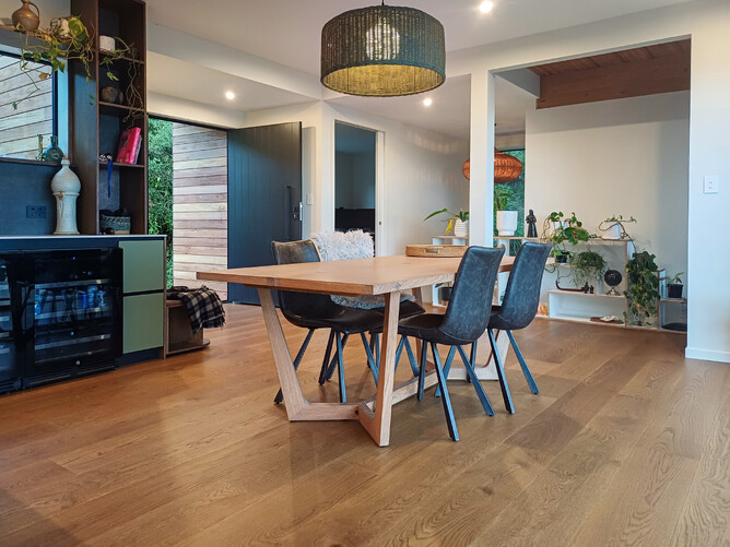A dining room with table in the middle and over hanging light. Flooring is natural French Oak timber flooring.