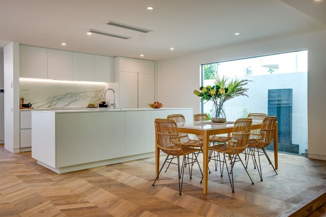 A modern kitchen with natural tones and a beautiful natural coloured chevron wood floor.