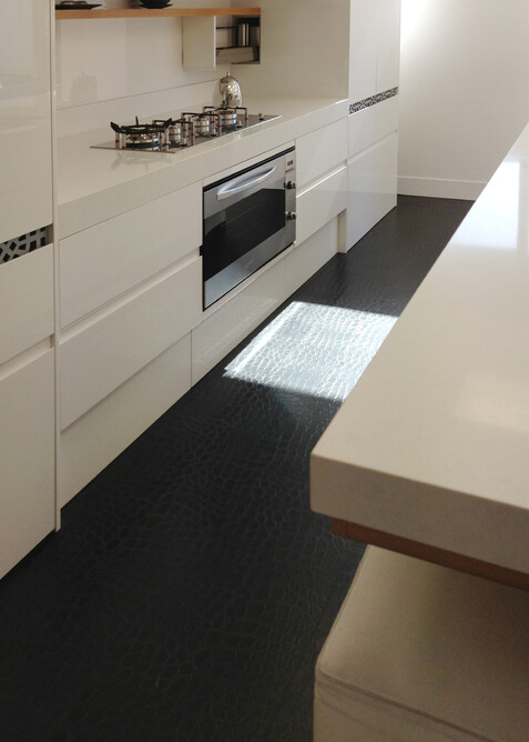 Black leather floor showing leather texture in a kitchen with white cabinets.