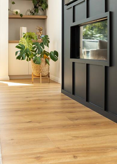 A black fireplace with wood look laminate flooring in natural tones.